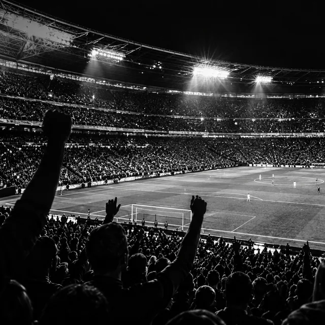 Supporters watching football in a floodlit stadium